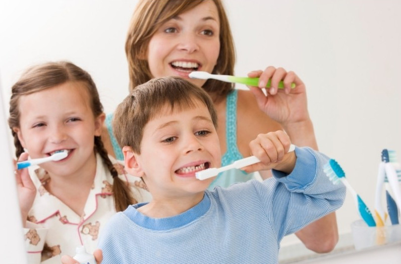 en barnfamilj borstar tänderna